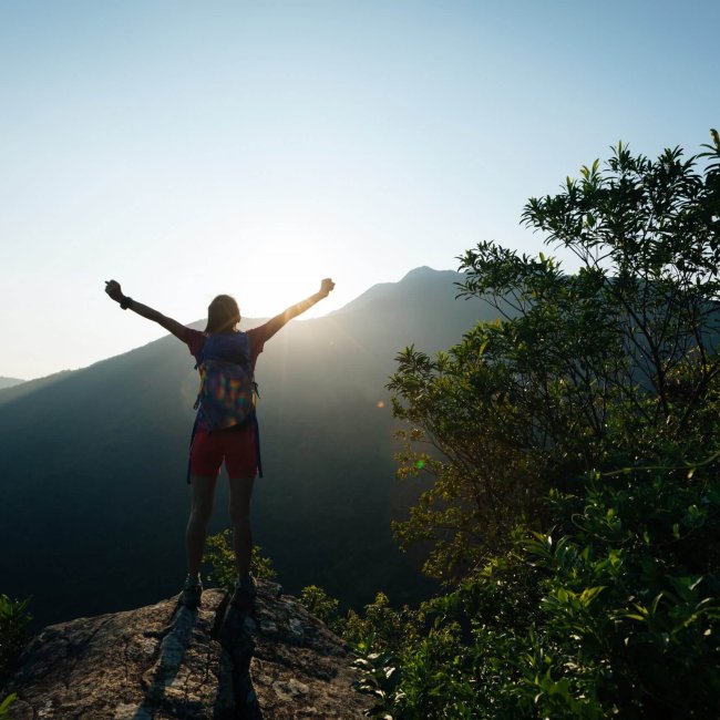 successful hiker hiking on summer sunrise mountain top